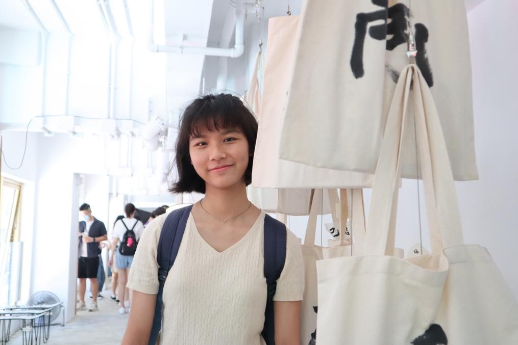 Student stood next to a row of tote bags