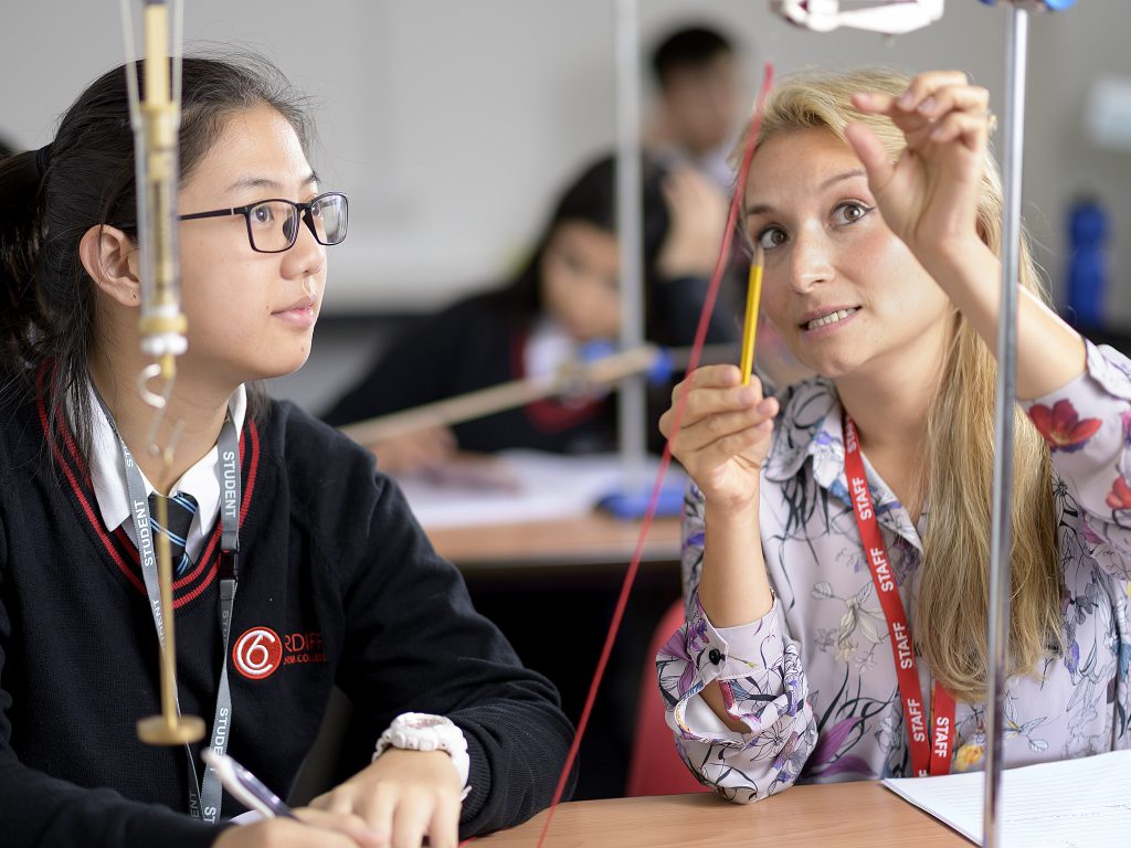 A science teacher helping a student at a sixth form college in Cardiff