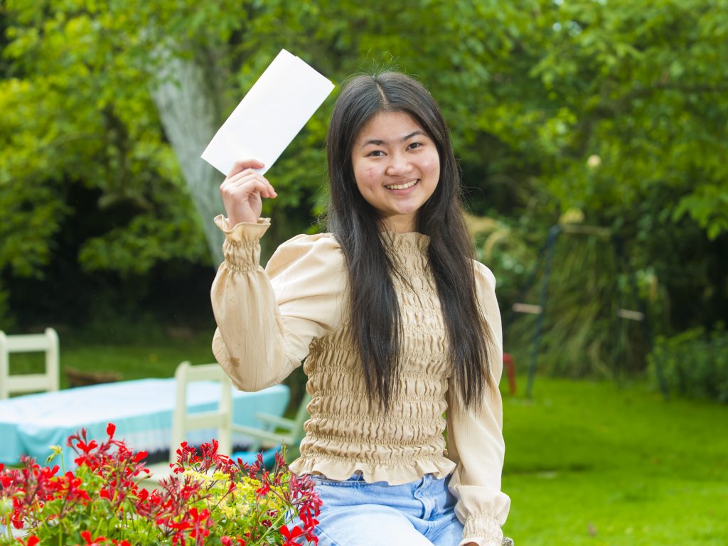 A student from a private school in Cardiff holding her exam results and smiling